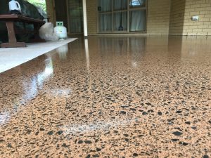 outdoor patio grind and seal close up of a patio with terracotta concrete floor and full stone exposure