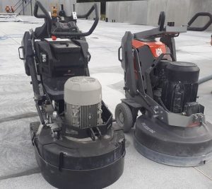 concrete-grinding-machine-taupo-tauranga-hamilton-wellington-napier close up image of 2 concrete grinding machines side by side on a part finished concrete floor